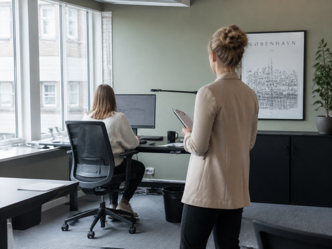 Rådgiver observerer en medarbeiders skrivebordsarbeidsplass under en arbeidsmiljøanalyse