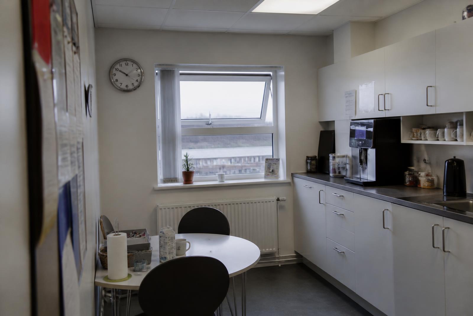 Personalekøkken med åbent vindue, kaffemaskine og lille spisebord